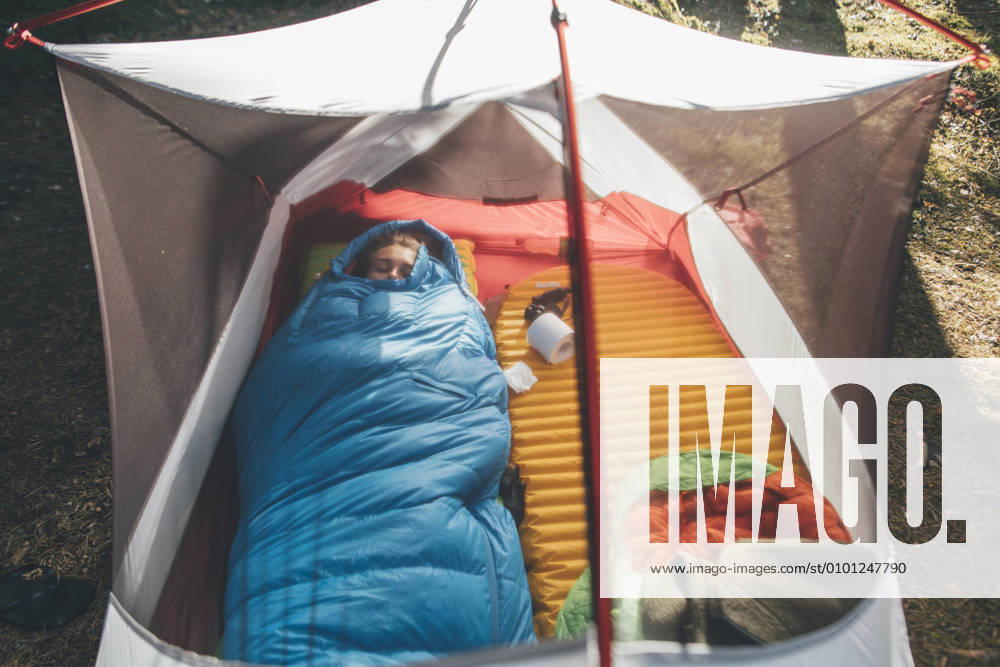 Young woman sleeping in sleeping bag in a tent model released Symbolfoto GUSF03701