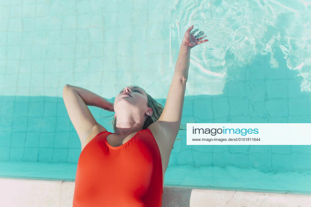 Woman wearing red swimsuit lying at the poolside model released Symbolfoto property released ERRF03663
