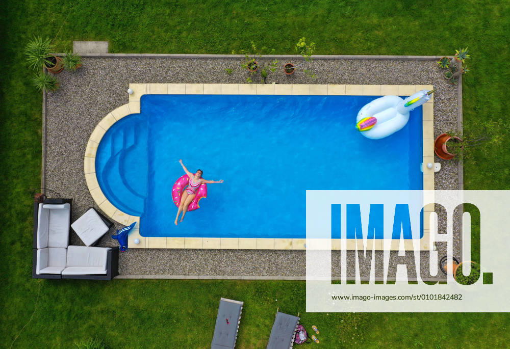 Trend in the Corona Pandemic The own swimming pool in the garden provides refreshment in summer when the outdoor pools are closed Aerial view of a garden pool in Unterallgäu Teenager sunbathing on a floating tyre in the water Modelreleased 26 06 2020, Swimming pool in own garden 26 06 2020, Swimming pool in own garden