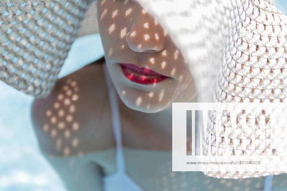 Close-up of young woman with red lipstick on lips wearing hat in swimming pool model released Symbolfoto JPTF00554