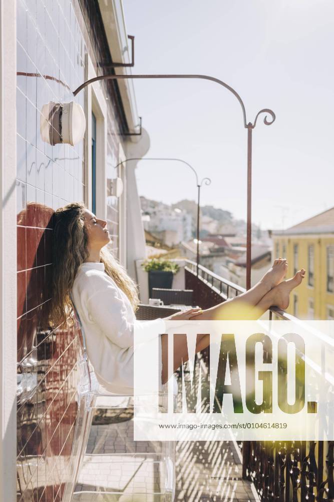 Serene young woman relaxing on sunny apartment balcony, Lisbon, Portugal