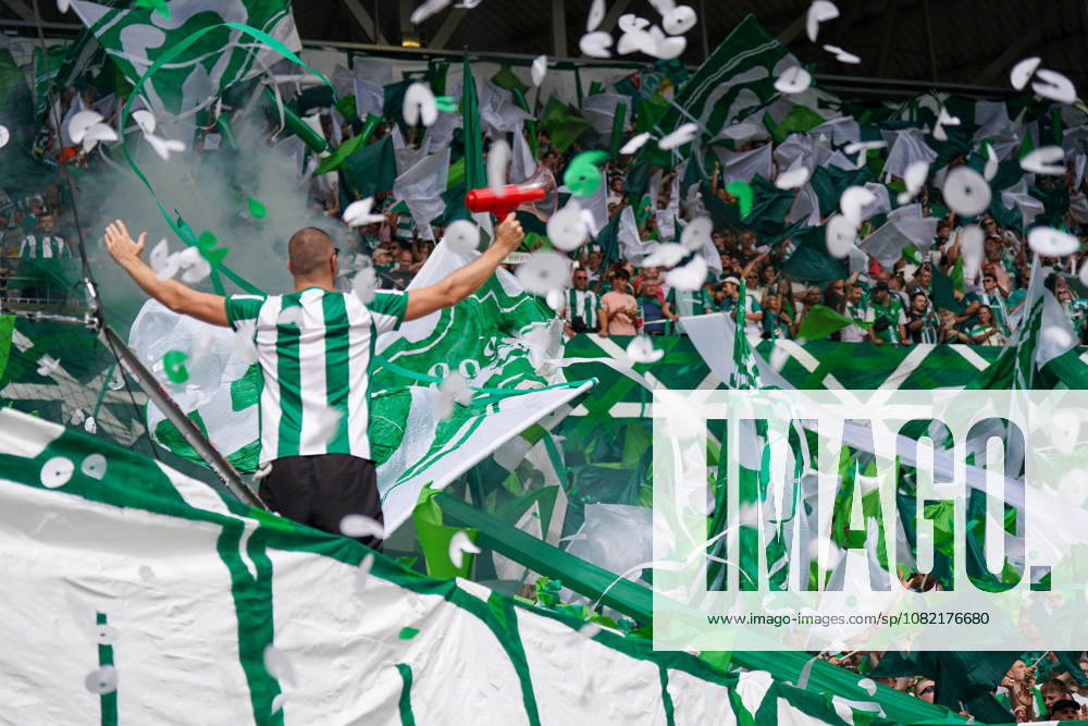 Deutschland: Fussball Bundesliga Saison 2026 - 2027, 1. Spieltag - SC Freiburg vs Werder Bremen - Europa Park Stadion (Freiburg): Fankurve von Werder Bremen im Stadion: Vorsänger mit Megafon vor dicht gedrängten Fans, umgeben von großen grün-weißen Schwenkfahnen. Grüner Rauch, Konfetti und Luftschlangen prägen die Choreographie. Zuschauer, Fans, Ultras, Supporter, Tribüne, Fanblock, Fankultur, Fanchoreo, Choreographie, Fahnenmeer, Megafon, Rauch, Pyrotechnik, Konfetti, Stimmung, Emotionen.