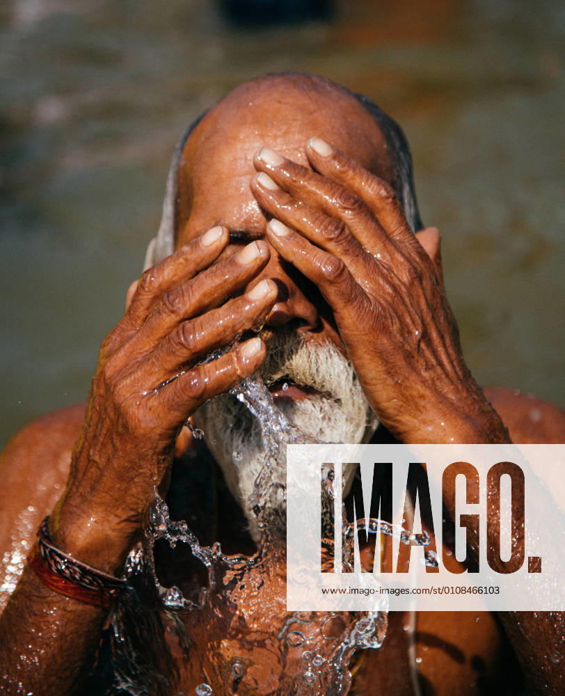 IMAGO Creative: 2021 Favoriten Allahabad, India - February, 2018:gray-haired man splashing and performing ritual bath in water in Prayag Kumbh Mela Festival