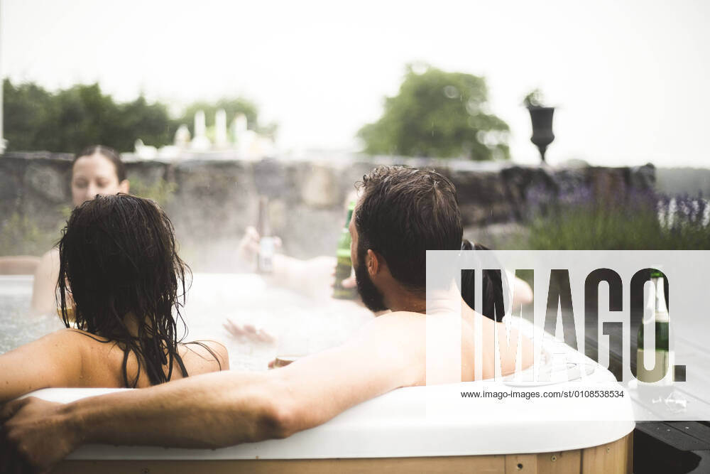 Male and female friends enjoying in hot tub during weekend getaway , model released, property released