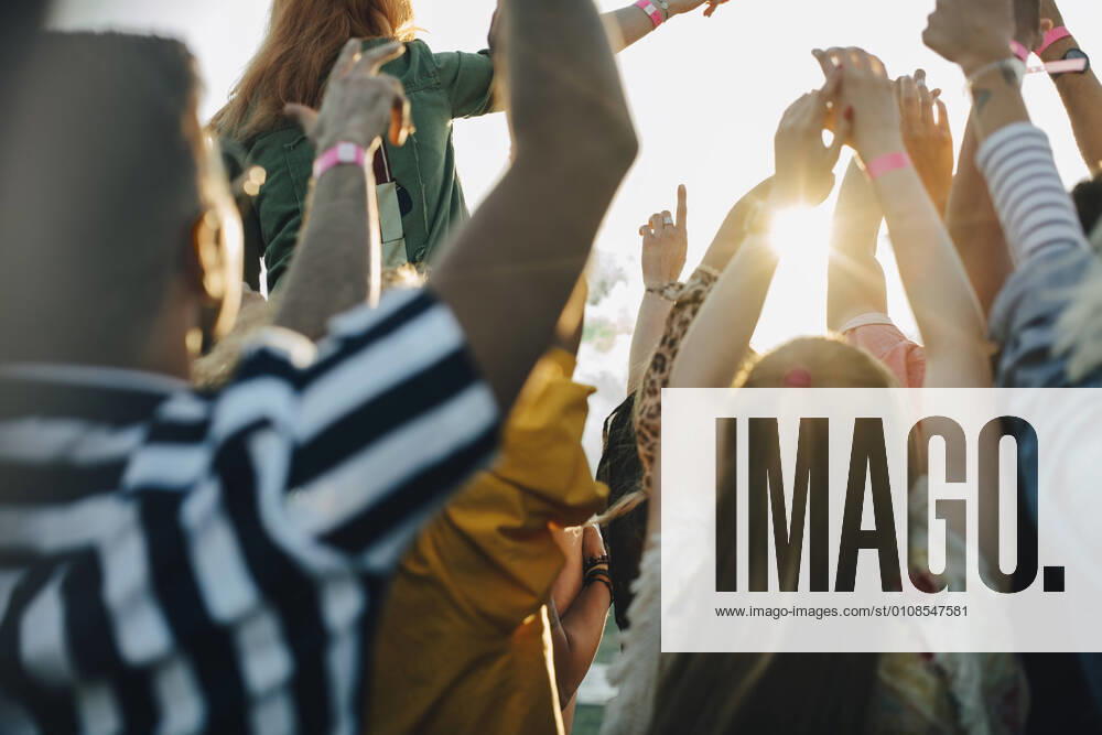 Rear view of crowd with arms raised enjoying in music festival , model released