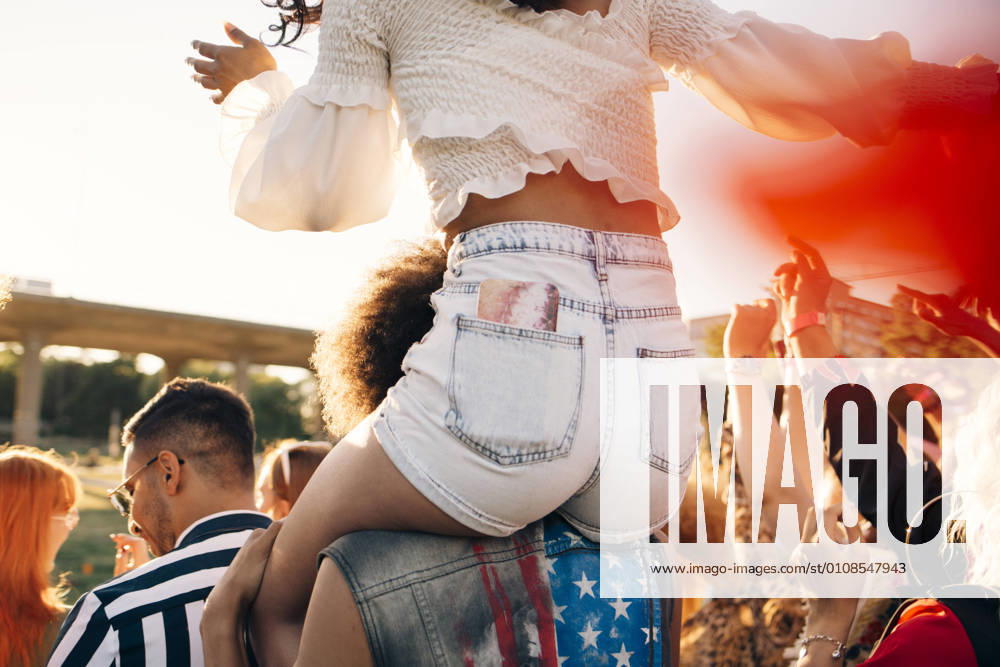 Man carrying friend on shoulder while enjoying at music festival , model released
