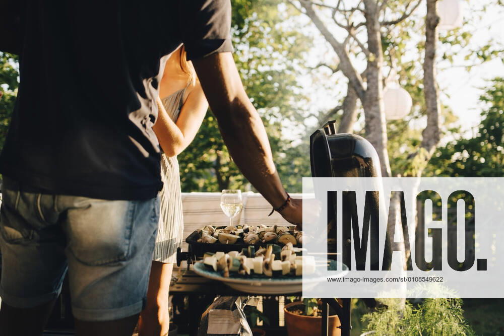 Midsection of friends grilling vegetables in barbecue for dinner party , model released, property released