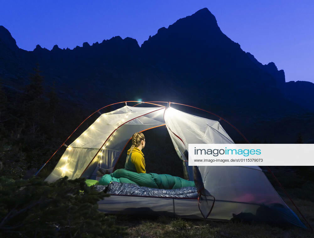 Woman sitting in illuminated tent on mountain at night Crestone, CO, United States CR_BRHU210312A-678789-01 ,model released, Symbolfoto