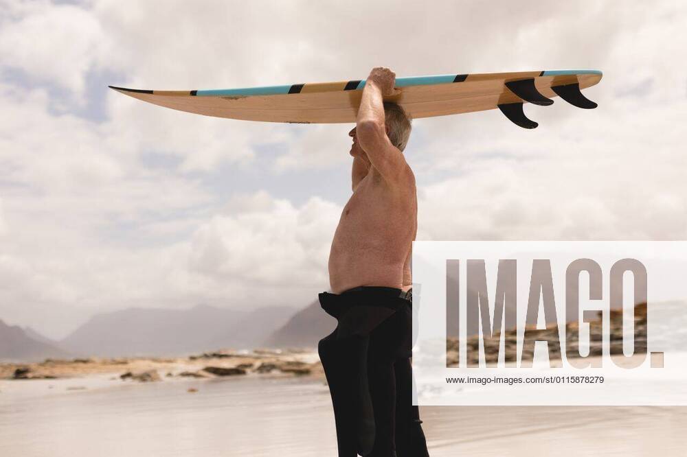 IMAGO Creative: Sommer Sport - Strand Senior man carrying surfboard on his head at beach Side view of active senior man carrying surfboard on his head at beach against relief background, model released, capetown, 12.02.2019, 1228311.jpg, senior citizen, aged, retired, pensioner, active senior, sportwear, standing, holding, smiling, surfer, surfboard, surfing, water sport, sport, beach, shore, ocean, wave, cloud, cloudy, sky, nature, environment, tranquility, serenity, calm, peaceful, scenic, beautiful, travel, travel destination, tourism, holiday, vacation, shirtless, diving suit, background, mountains, relief 70s, Senior, Elderly, Man, Male, Caucasian, Senior Men, Caucasian Ethnicity Outdoors