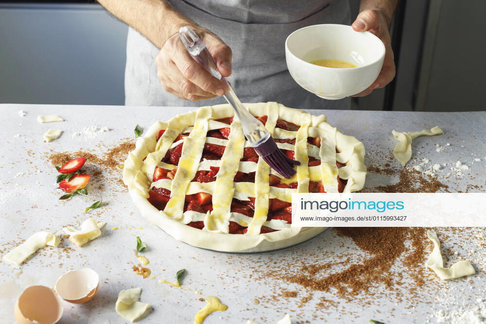 Hands of man applying egg wash to raw strawberry pie model released Symbolfoto property released IFRF00457