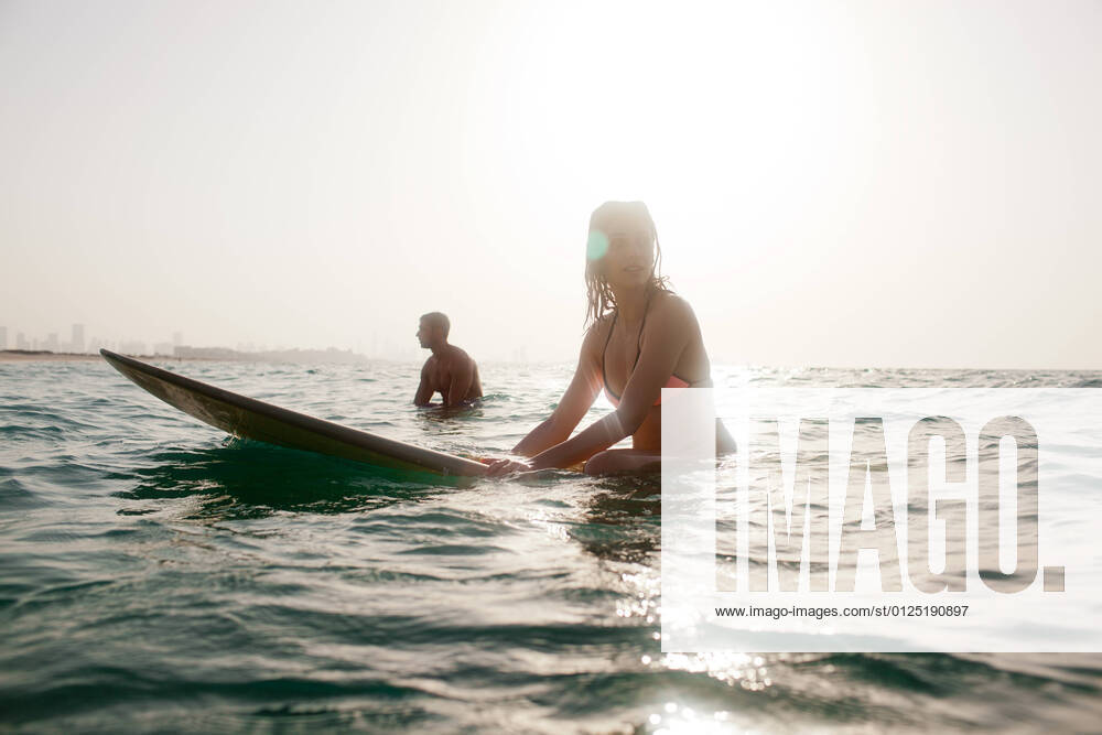 IMAGO Creative: Sommer Sport - Strand Expat couple surfing at sea.