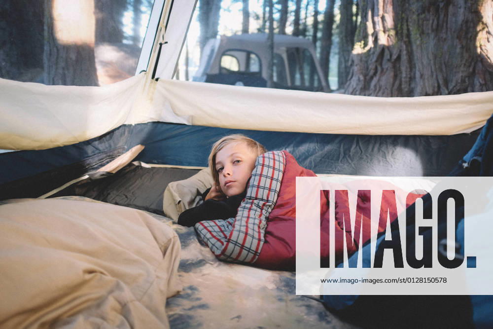 IMAGO Creative: Klimawandel - Umwelterziehung Sleepy Boy wrapped in Sleeping Bag Wakes up in the Woods Yuba Pass, CA, United States CR_CXBA210330A-682472-01 ,model released, Symbolfoto
