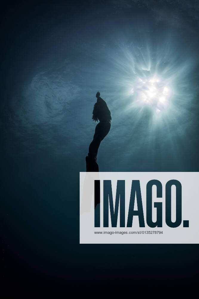 IMAGO Creative: Sommer Sport - Strand Underwater view of silhouetted female free diver moving up towards sun rays, New Providence, Bahamas, 18.09.2017,