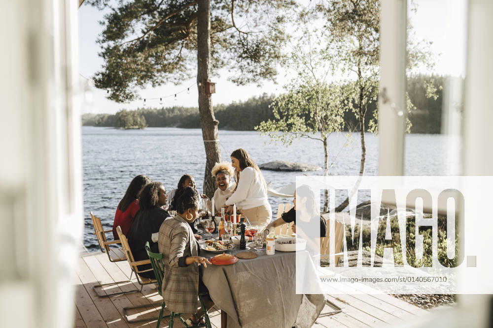 Cheerful female friends enjoying while having food at dinner party on sunny day Sweden, Gothenburg, model released, property released