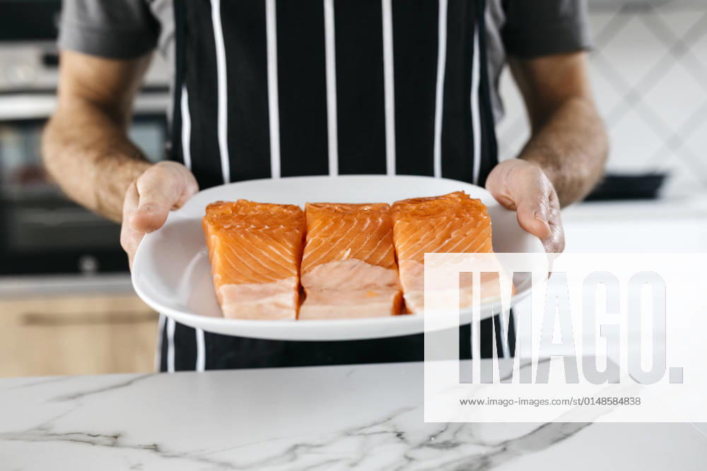 Man holding plate with raw fish slices in kitchen at home model released property released, JRFF05249