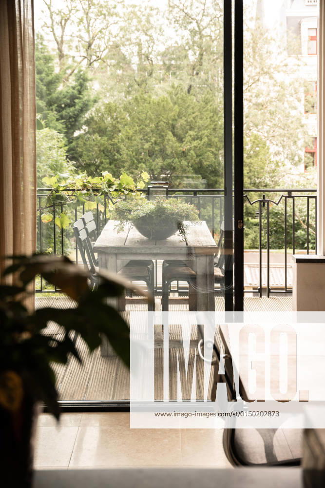Wooden table and flower in light room near transparent door of terrace with wooden table and green plant near fence and trees in city, Property released CasaMedia_Keizersgracht371C_32.jpg