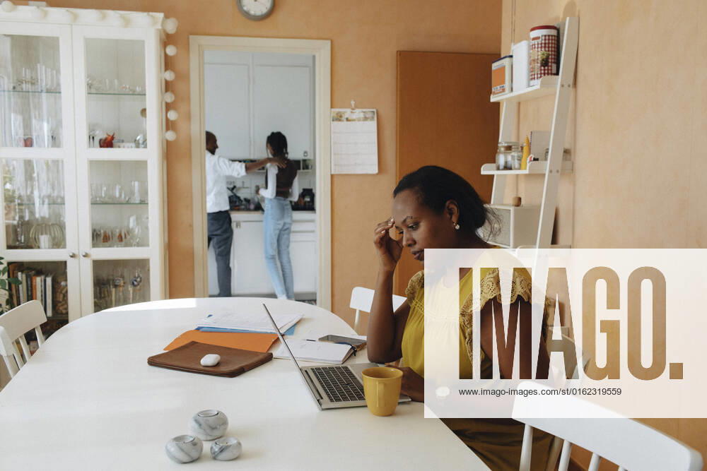 IMAGO Creative: Business, Innovative Technologie-Lösungen Female freelancer with head in hand using laptop while sitting at table Sweden, Stockholm, model released, property released