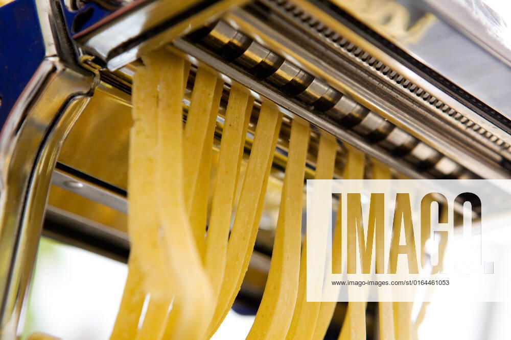 Fettuccine coming out of a manual pastamachine - shallow depth of field with focus on the pasta