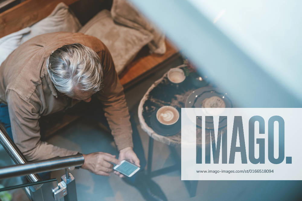 IMAGO Creative: Business, Innovative Technologie-Lösungen Senior man text messaging on smart phone at cafe model released, Symbolfoto property released, JOSEF11561