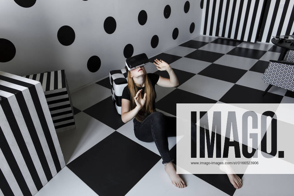 IMAGO Creative: Business, Innovative Technologie-Lösungen Girl wearing virtual reality headset sitting on checkered floor model released, Symbolfoto property released, LLUF00810