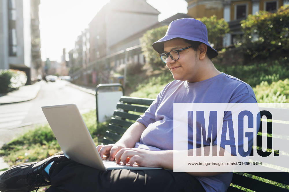 Smiling teenage boy using laptop on bench in park model released, Symbolfoto, MEUF07370