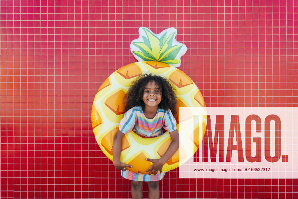 Cute girl wearing swimming float standing in front of red wall model released, Symbolfoto, OIPF02207