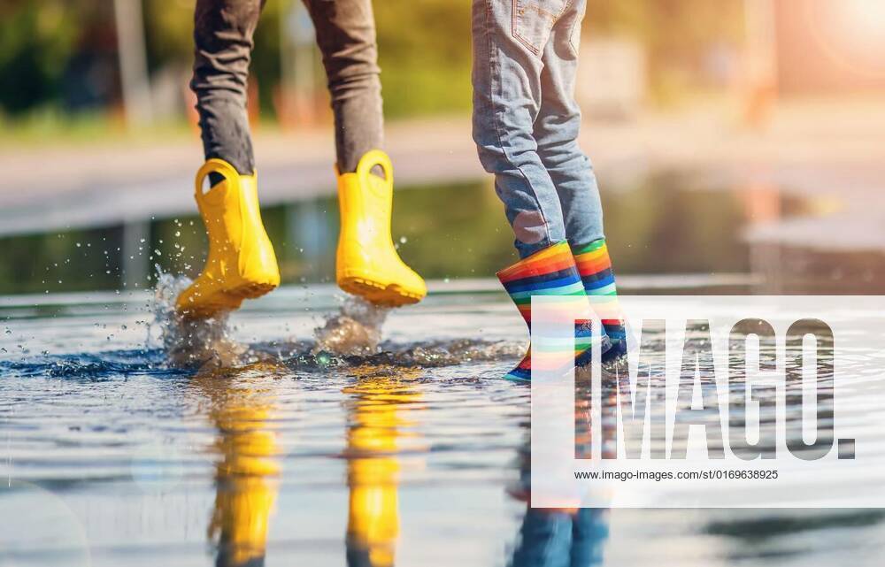 Children jumping in the puddle in rubber boots., Children jumping in the puddle in rubber boots. Concept of childhood and friendship., Children jumping in the puddle in rubber boots. Concept of childhood and friendship. model released, Symbolfoto , 11.08.2022,