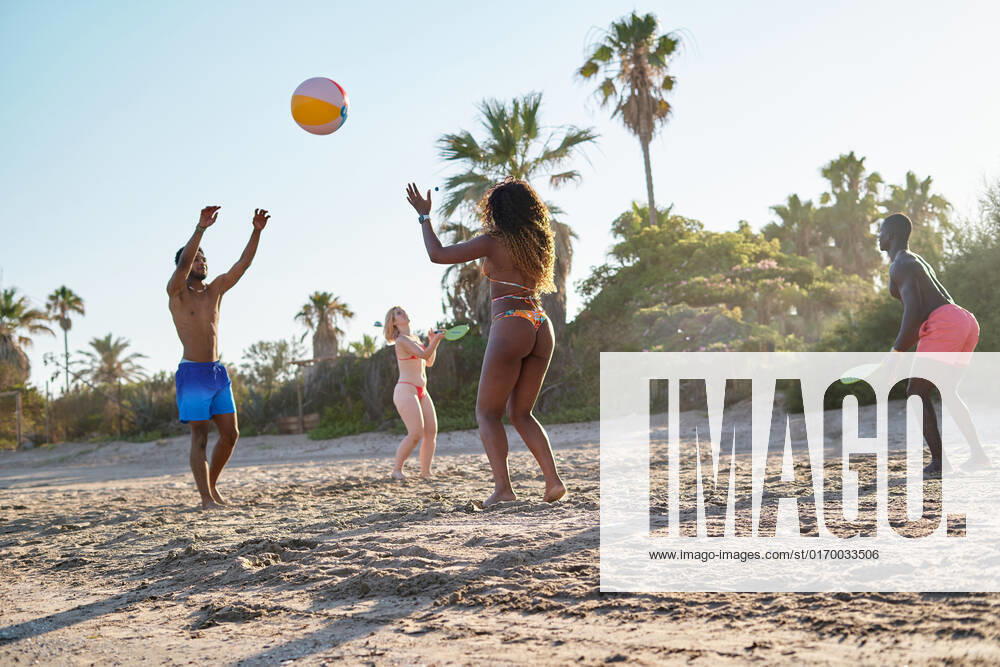 Low angle of diverse men and women tossing ball and playing beach tennis while spending summer weekend day on sandy seashore together, Model released AdalbertoRodriguez_ID644_23634_068