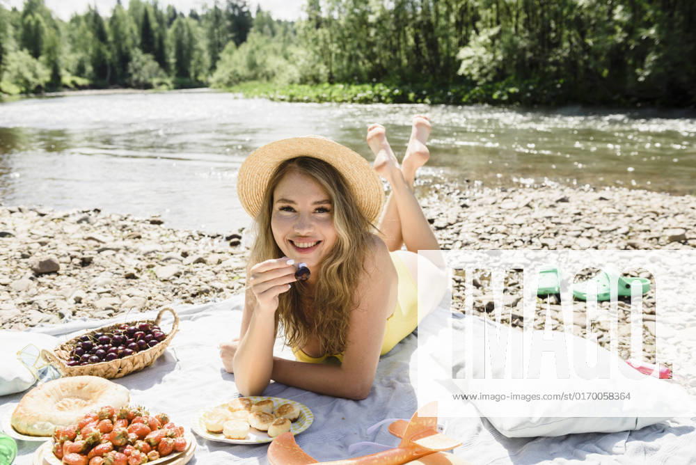 Woman holding cherry lying on blanket at riverbank model released, Symbolfoto, VBUF00150
