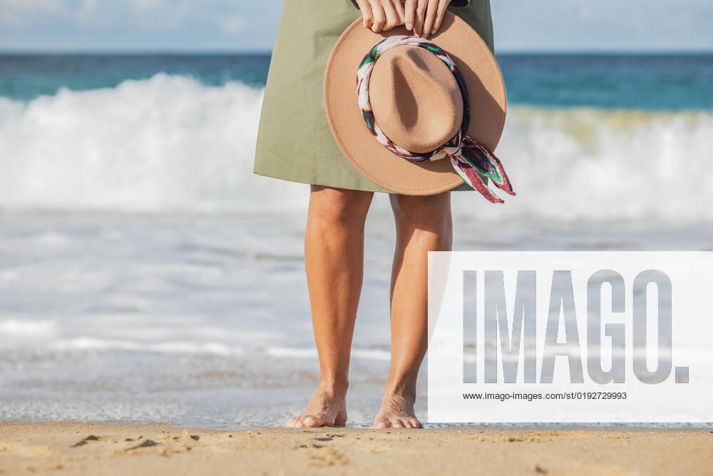 Crop anonymous barefoot woman standing on sandy beach along waving sea water, Model released HodeiUnzueta_ID1044_39269_052