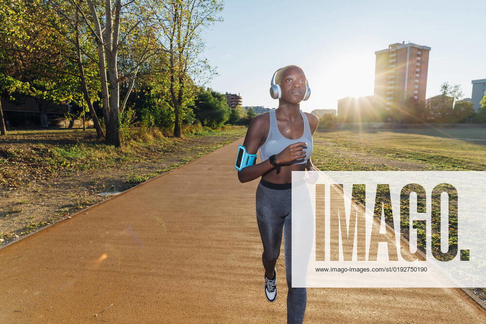 IMAGO Creative: Business, Innovative Technologie-Lösungen Young athlete listening to music on headphones and running in park model released, Symbolfoto, MEUF08255