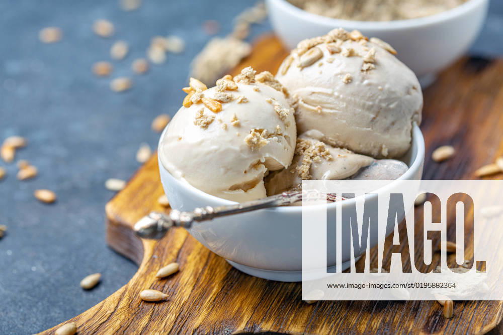 Ice cream with halva and sunflower seeds close up. Homemade sundae with sunflower oil and halva in a white ceramic bowl close-up, selective focus.