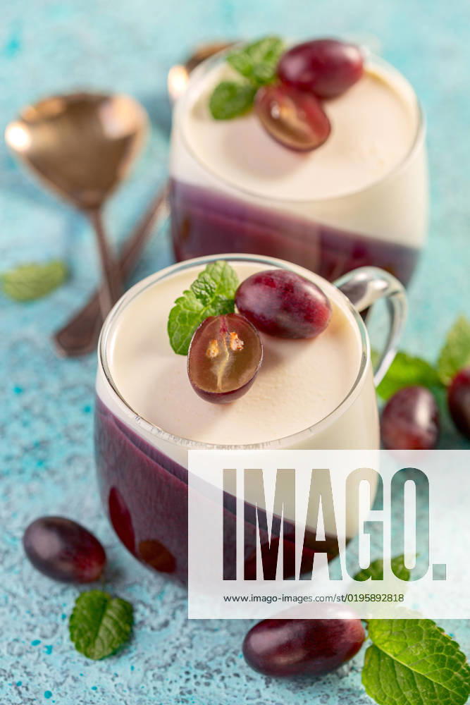 Panna cotta is a traditional Italian dessert. Traditional Italian dessert vanilla and berry Panna cotta served in glass cups on a wooden serving board, selective focus.