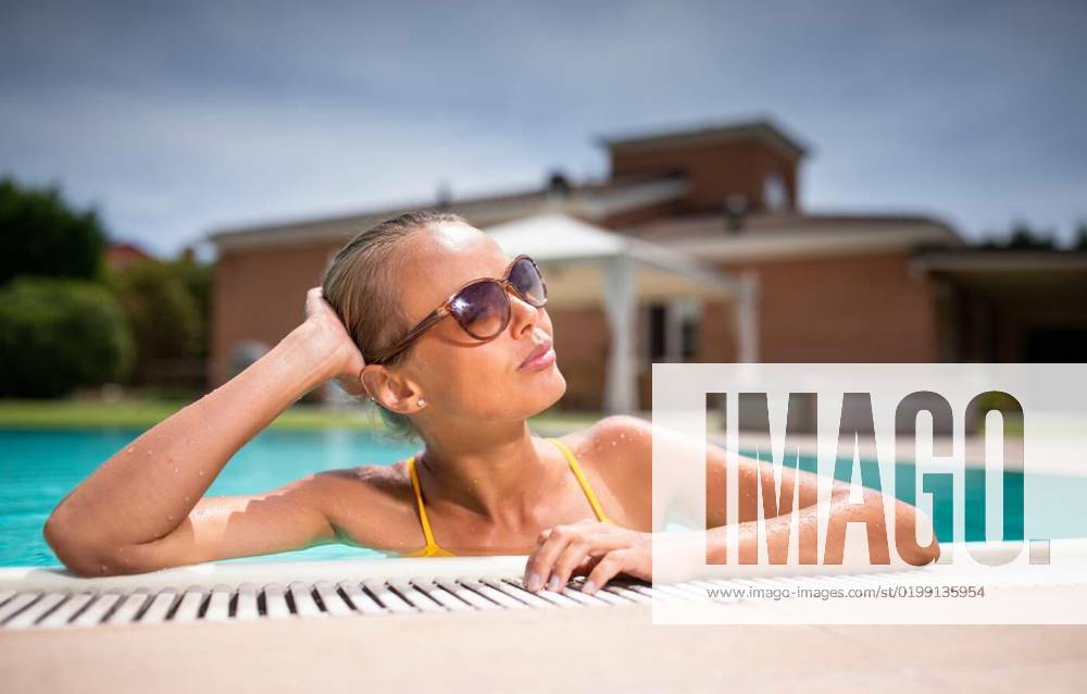 Young Beautiful Suntanned Woman wearing sunglasses relaxing next to a Swimming Pool on a lovely Summer Day, Young Beautiful Suntanned Woman wearing sunglasses relaxing next to a Swimming Pool on a lovely Summer Day, Young Beautiful Suntanned Woman wearing sunglasses relaxing next to a Swimming Pool on a lovely Summer Day model released, Symbolfoto , 22.12.2022,