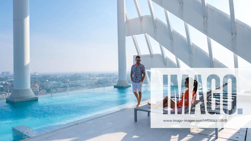IMAGO Creative, Urban Lifestyle couple men and women relaxing at a rooftop pool of a luxury hotel couple of men and women relaxing at a rooftop pool of a luxury hotel. Asian Thai women and caucasian men relaxing by pool on a rooftop