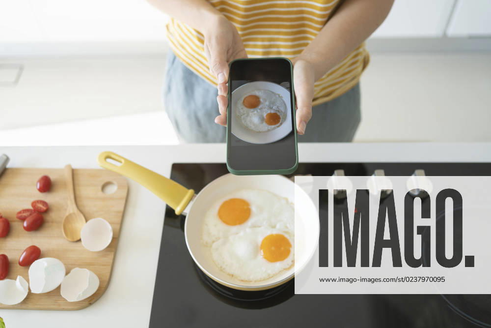 Woman photographing fried eggs with smart phone at home model released, Symbolfoto property released, SVKF01264