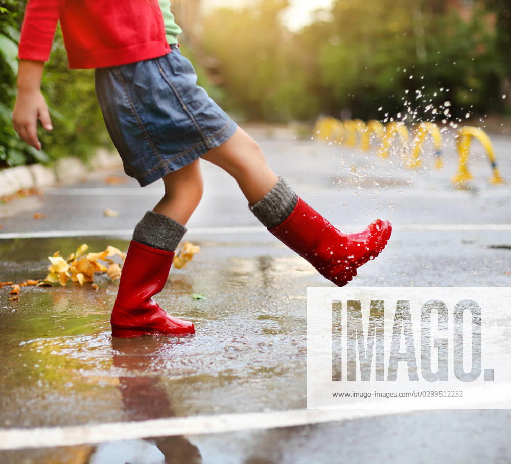 Child wearing red rain boots jumping into a puddle Child wearing red rain boots jumping into a puddle. Close up ,model released, Symbolfoto