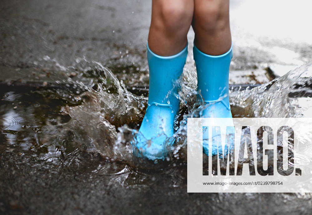 Child wearing blue rain boots jumping into a puddl Child wearing blue rain boots jumping into a puddle. Close up ,model released, Symbolfoto