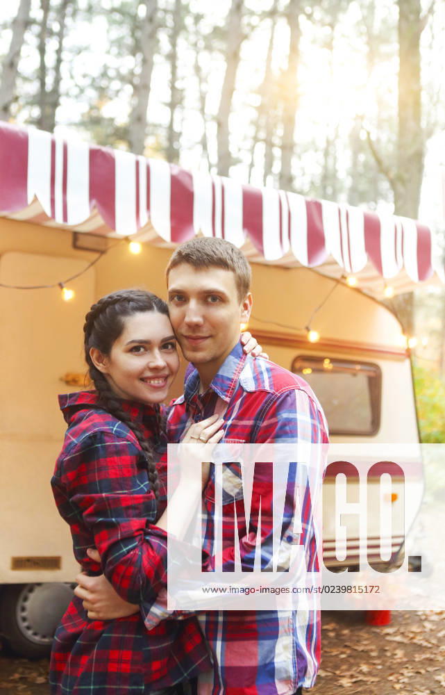 Portrait of romantic couple smiling while holding hands near house on wheels outdoors Portrait of romantic couple man and woman smiling while hugging near house on wheels outdoors ,model released, Symbolfoto