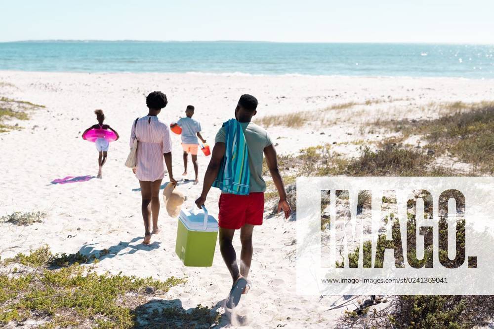 Rear view of african american family with swimming float, cooler walking at beach towards seascape Rear view of african american family with swimming float, cooler walking at beach towards seascape. Copy space, unaltered, parents, together, childhood, picnic, nature, vacation, enjoyment, summer., model released, , property released, Cape Town, South Africa, 19.01.2023, 3991010.jpg, people,rear view,african american,family,swimming,float,cooler,walking,beach,towards,seascape,copy space,unaltered,parent,together,childhood,picnic,nature,kid,mother,sea,ocean,little,daughter,coast,summer,vacation,sand,water,mom,fun,happiness,father,son,happy,outdoor,shore,love,rear,view,african,american,copy,space Mid Adult,Man,Male,Black,Woman,Female,Child,Gir