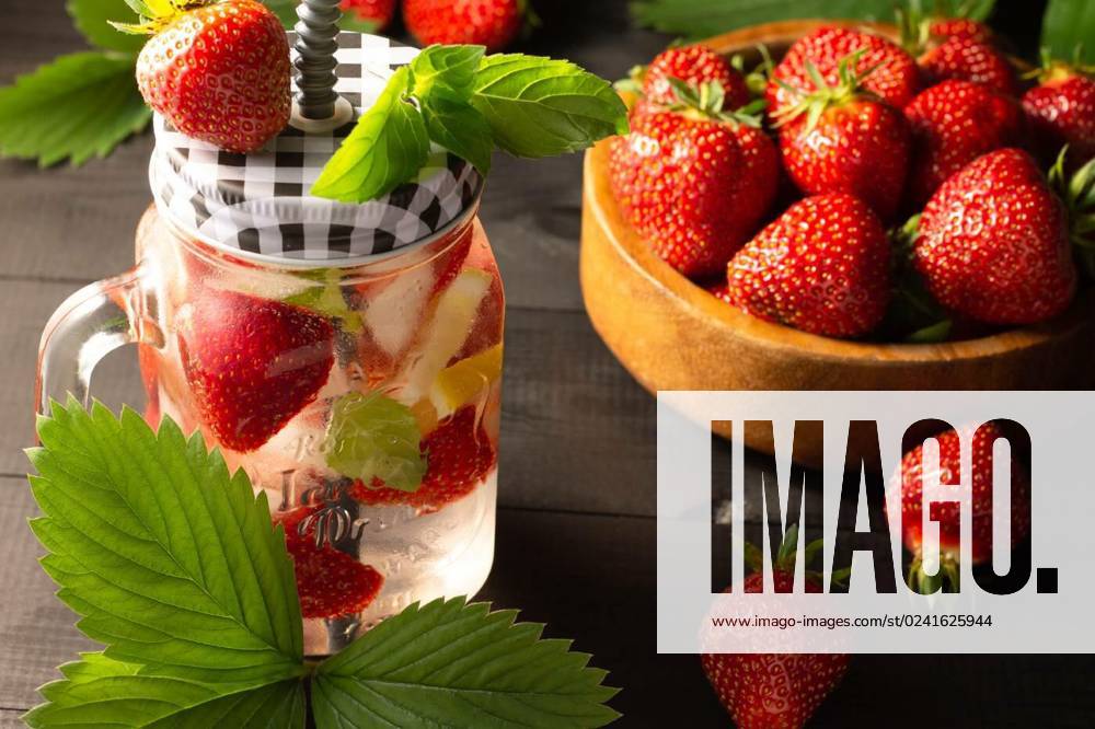 Summer cold drink with mint, ice, lemon and strawberries and wooden bowl of fresh strawberries on black wooden surface., Summer cold drink with mint, ice, lemon and strawberries and a wooden bowl of fresh strawberries on a black wooden surface., Summer cold drink with mint, ice, lemon and strawberries and a wooden bowl of fresh strawberries on a black wooden surface., 26.03.2023,