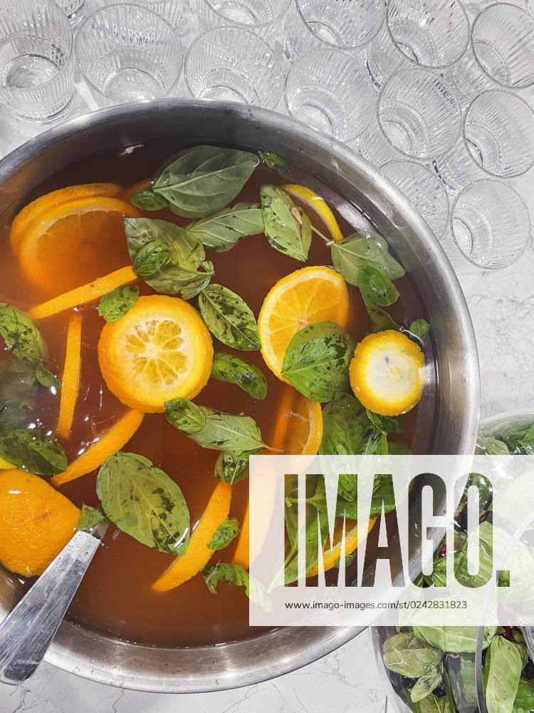 Punch large bowl with oranges and mint. Boiled citrus juice. Drink with a variety of fruits close up. Orange alcoholic cocktail. Empty glasses on the background table. Punch large bowl with oranges and mint. Boiled citrus juice. Drink with a variety of fruits close up. Orange alcoholic cocktail. Empty glasses on the background table. Lifestyle and party concept.