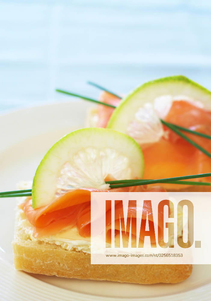 Smoked salmon and cream cheese starter on white bread with slice of lemon and chives