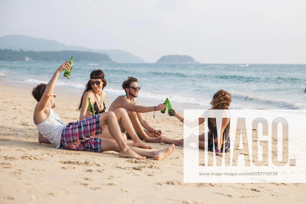 Happy friends toasting drink bottles sitting at beach model released, Symbolfoto, IKF00282