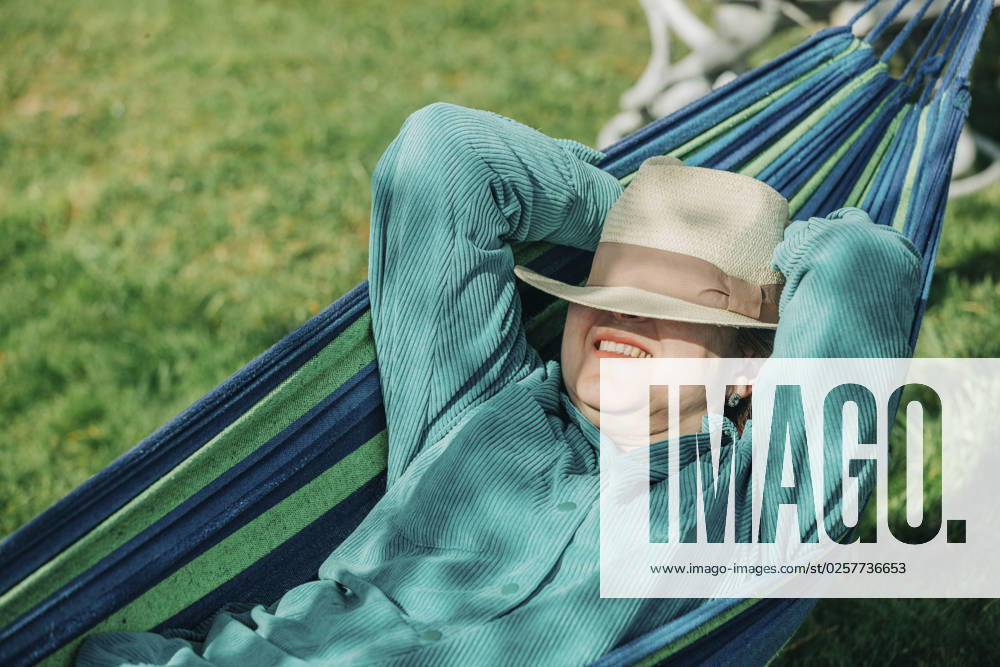 Senior woman with hands behind head relaxing on hammock at sunny day model released, Symbolfoto, VSNF00786