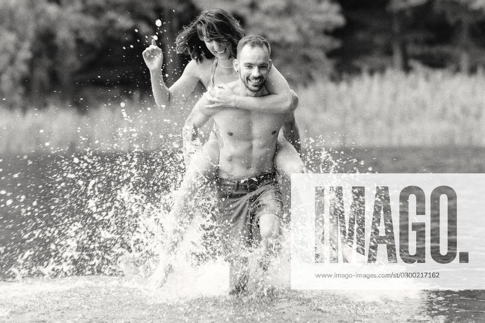 CREATIVE - Paar am See in Berlin Berlin, Deutschland - 25. Juli 2023: (CREATIVE) Ein Mann trägt Huckepack eine Frau (Models) und genießen einen Sommertag an der Krummen Lanke, einem See in Berlin. Berlin