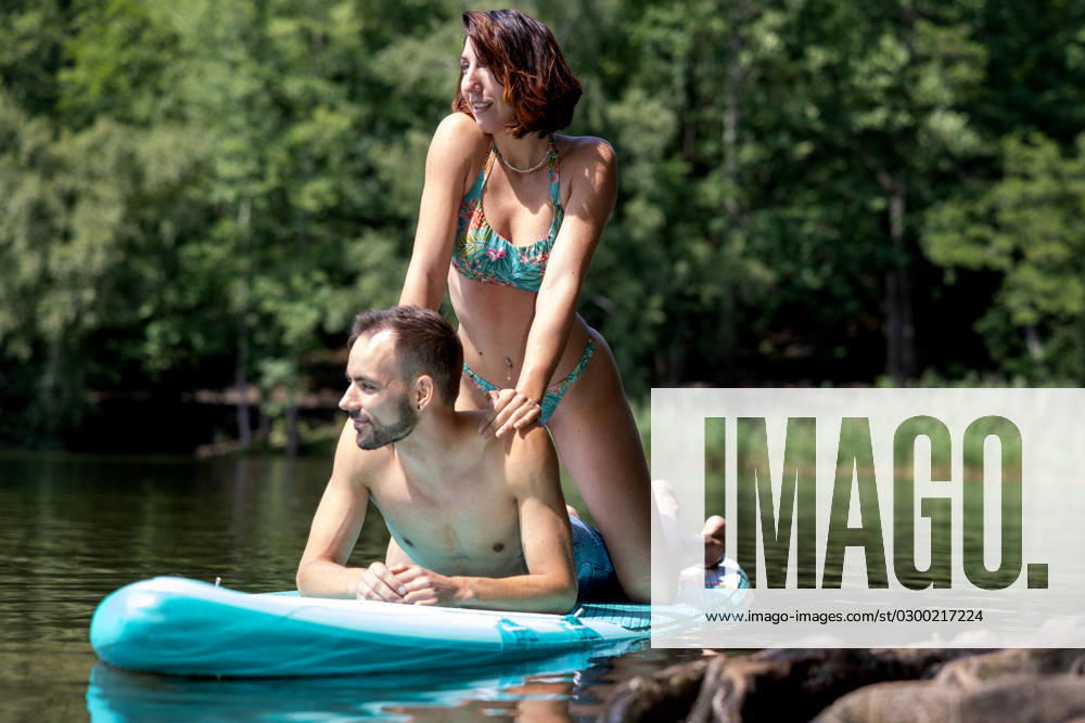 CREATIVE - Paar am See in Berlin Berlin, Deutschland - 25. Juli 2023: (CREATIVE) Ein Mann und eine Frau (Models) genießen auf einem SUP (stand up paddle boat) einen Sommertag an der Krummen Lanke, einem See in Berlin. Berlin
