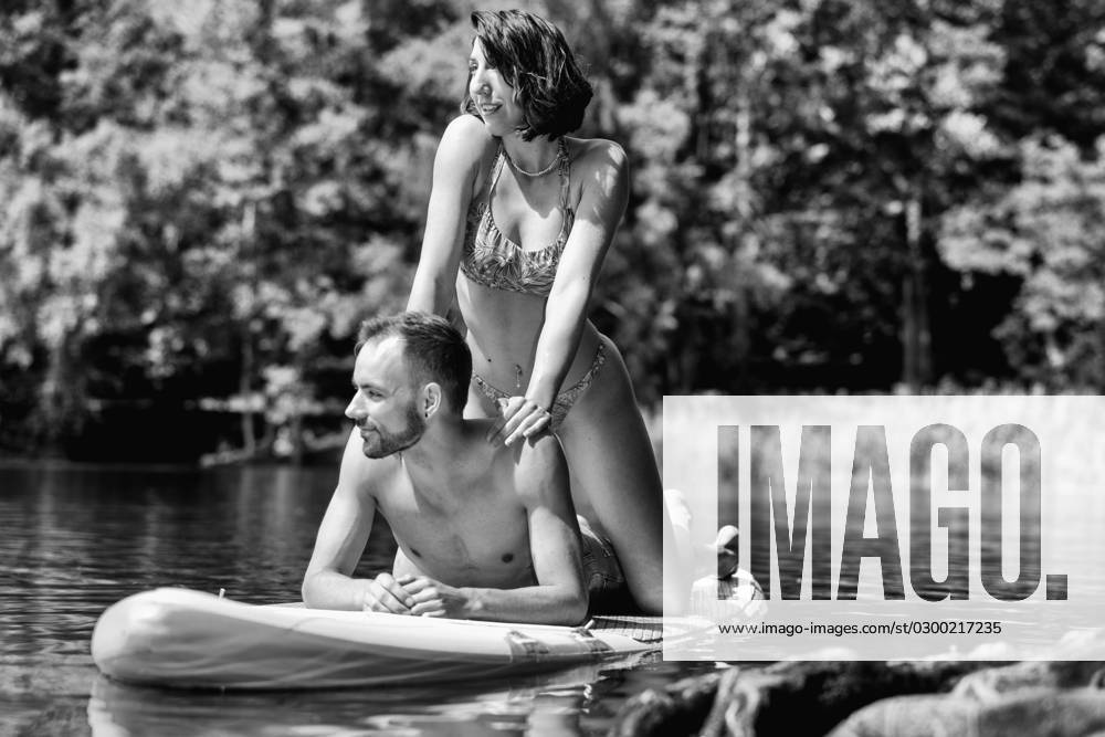 CREATIVE - Paar am See in Berlin Berlin, Deutschland - 25. Juli 2023: (CREATIVE) Ein Mann und eine Frau (Models) genießen auf einem SUP (stand up paddle boat) einen Sommertag an der Krummen Lanke, einem See in Berlin. Berlin