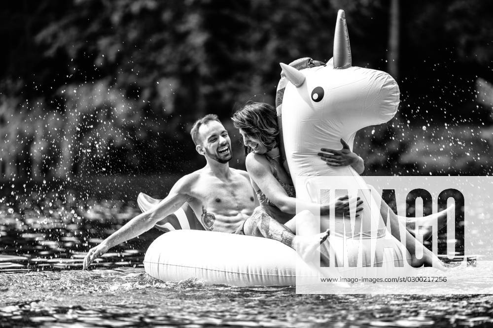 CREATIVE - Paar am See in Berlin Berlin, Deutschland - 25. Juli 2023: (CREATIVE) Ein Mann und eine Frau (Models) genießen auf einem aufgeblasenen Einhorn einen Sommertag an der Krummen Lanke, einem See in Berlin. Berlin