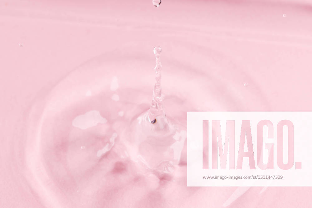Close up of water drop falling into water with ripples and copy space on pink background. Water, liquid and colour concept.
